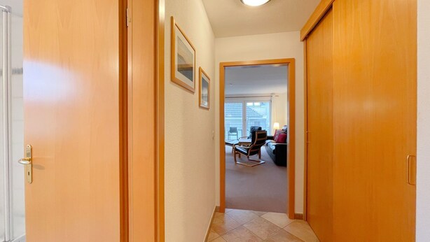 A hallway with wooden doors leading to a living area with a sofa and a chair.