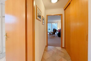 A hallway with wooden doors leading to a living area with a sofa and a chair.