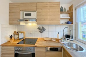 A modern kitchen with wooden cabinets, a microwave, a toaster, a sink, and a dishwasher. - "Relaxation and comfort: Your vacation apartment on Usedom awaits you!" - (Loddin)