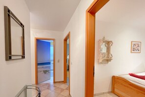 A bedroom with a wooden bed, a mirror, and a door leading to a bathroom.