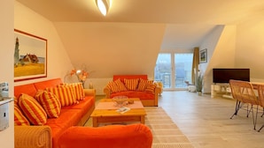 A modern living room with two orange sofas, a wooden coffee table, and a television.