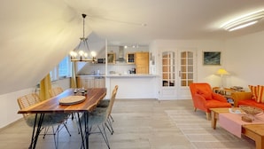 A modern apartment with a dining area, kitchen, and living space.