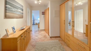 A hallway with a wooden cabinet, a patterned rug, and a large mirror.