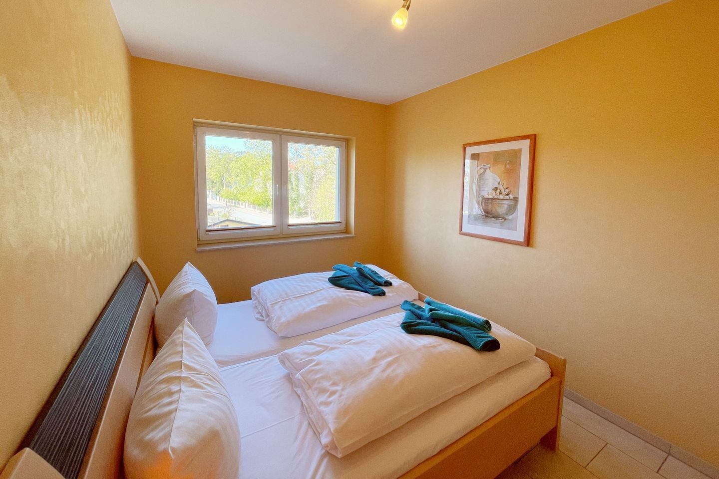 Un dormitorio con dos camas, una ventana y un cuadro en la pared.