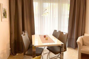 Ein moderner Essbereich mit einem rechteckigen Tisch, vier Stühlen und einer Vase darauf.