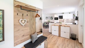 Une cuisine moderne avec des meubles blancs, un banc en bois et une décoration en forme de cœur.