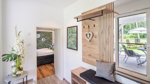 Une chambre moderne avec un lit, un banc doté d’un coussin, une étagère fixée au mur et une vue sur une terrasse extérieure.