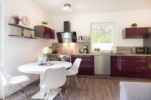 A modern kitchen with a dining area, stainless steel appliances, and a window providing natural light. - Hochwertig, Liebevoll Eingerichtetes, 85qm Großes, Ferienhaus für 4 Personen. - Gerhart-hauptmann (Loddin)