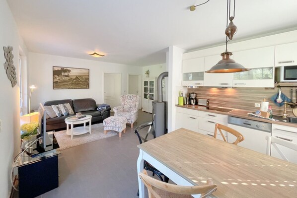 Een moderne keuken met witte kasten, een houten eettafel en een hanglamp.