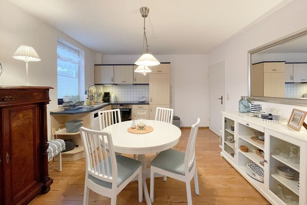 A modern kitchen with white cabinetry, a round dining table, and white chairs.