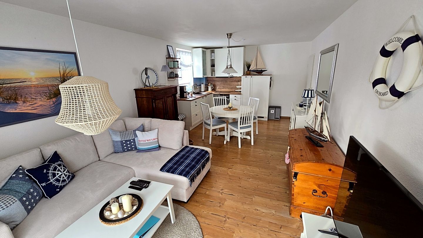 Un espacio habitable compacto con sofá, mesa de comedor y kitchenette.