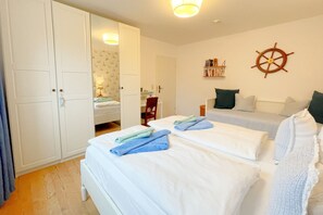 A bedroom with two beds, a wardrobe, a desk, and a bookshelf.