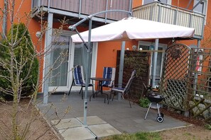 An outdoor patio with a table and chairs, a grill, and a covered seating area.
