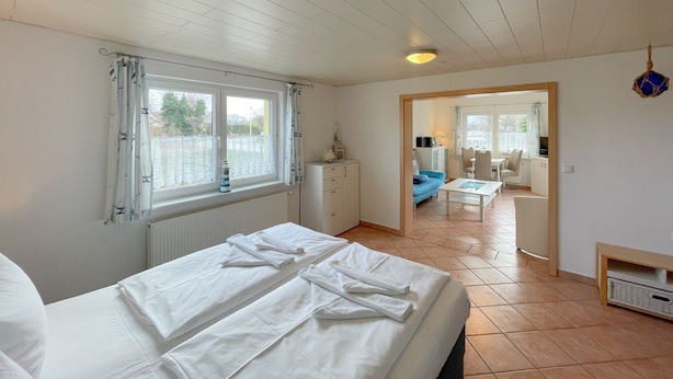 Et soveværelse med seng, et vindue, en radiator og udsigt til et opholdsområde.