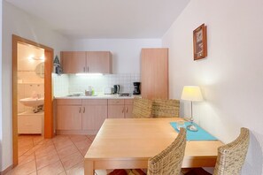 Une cuisine de taille réduite avec un coin repas comprenant une table, des chaises et une lampe.