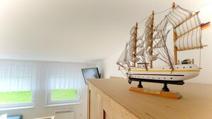 A model ship on a wooden table in a room with a window and a chair. - "Experience unforgettable days in the "Engel" vacation bungalow on the Baltic Sea!" - To (Ückeritz)