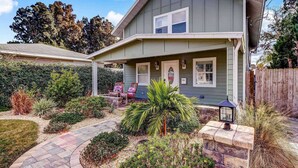 A two-story house with a covered porch, stone pathway, and various plants. - Florida Breeze (St. Augustine)
