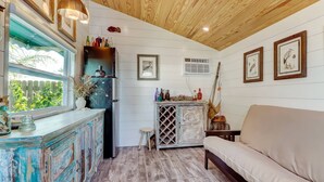 A rustic kitchen with a wooden ceiling, a white wall with framed pictures, and a beige sofa. - Florida Breeze (St. Augustine)