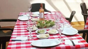 A dining table set with plates, glasses, and a bottle of wine, covered by a red and white checkered tablecloth. - Hotel Casa san rafael  (Villa de Leyva)