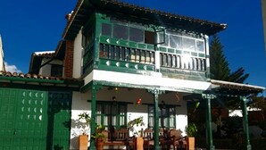 A two-story house with a balcony, a green door, and a tiled patio. - Hotel Casa san rafael  (Villa de Leyva)