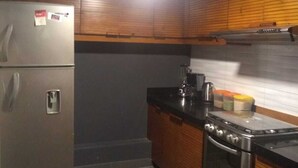 Eine kleine Küche mit Kühlschrank, Herd und Holzschränken.