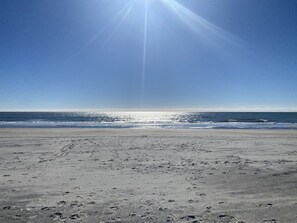 A beach with footprints in the sand and a clear sky.