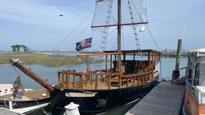 Un bateau en bois était amarré à un quai, avec une bouée de sauvetage, un feu blanc et un drapeau.
