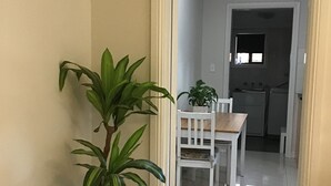 A hallway with a potted plant, a white chair, and a dining table. - Large one bedroom Cottage in the heart of St Marys (Saint Marys)