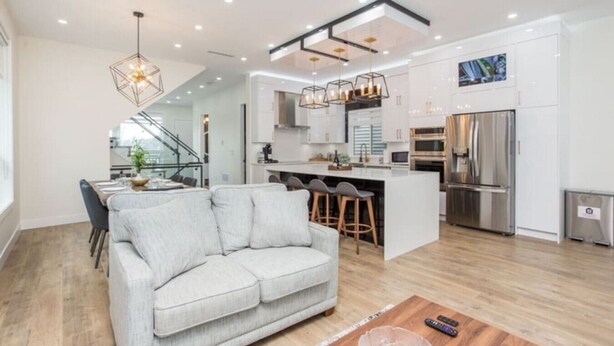 A modern kitchen with a central island, stainless steel appliances, and pendant lighting. - Gatsby`s Corner | King Bed | Near Parks & Golf (Surrey)