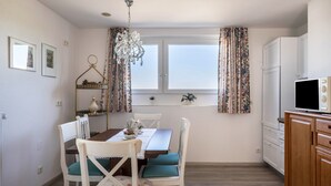 Un coin repas comprenant une table, des chaises, un lustre et une fenêtre avec des rideaux.
