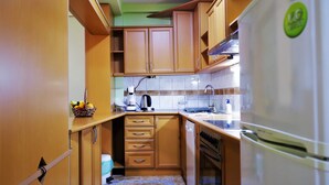 A compact kitchen with wooden cabinets, a built-in oven, a sink, and a refrigerator.