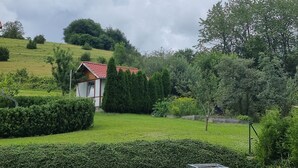A small house with a red roof, surrounded by well-maintained hedges and trees. - Holiday Apartment "Biosphärenblick" with Private Terrace, Shared Garden and Wi-Fi (Münsingen)