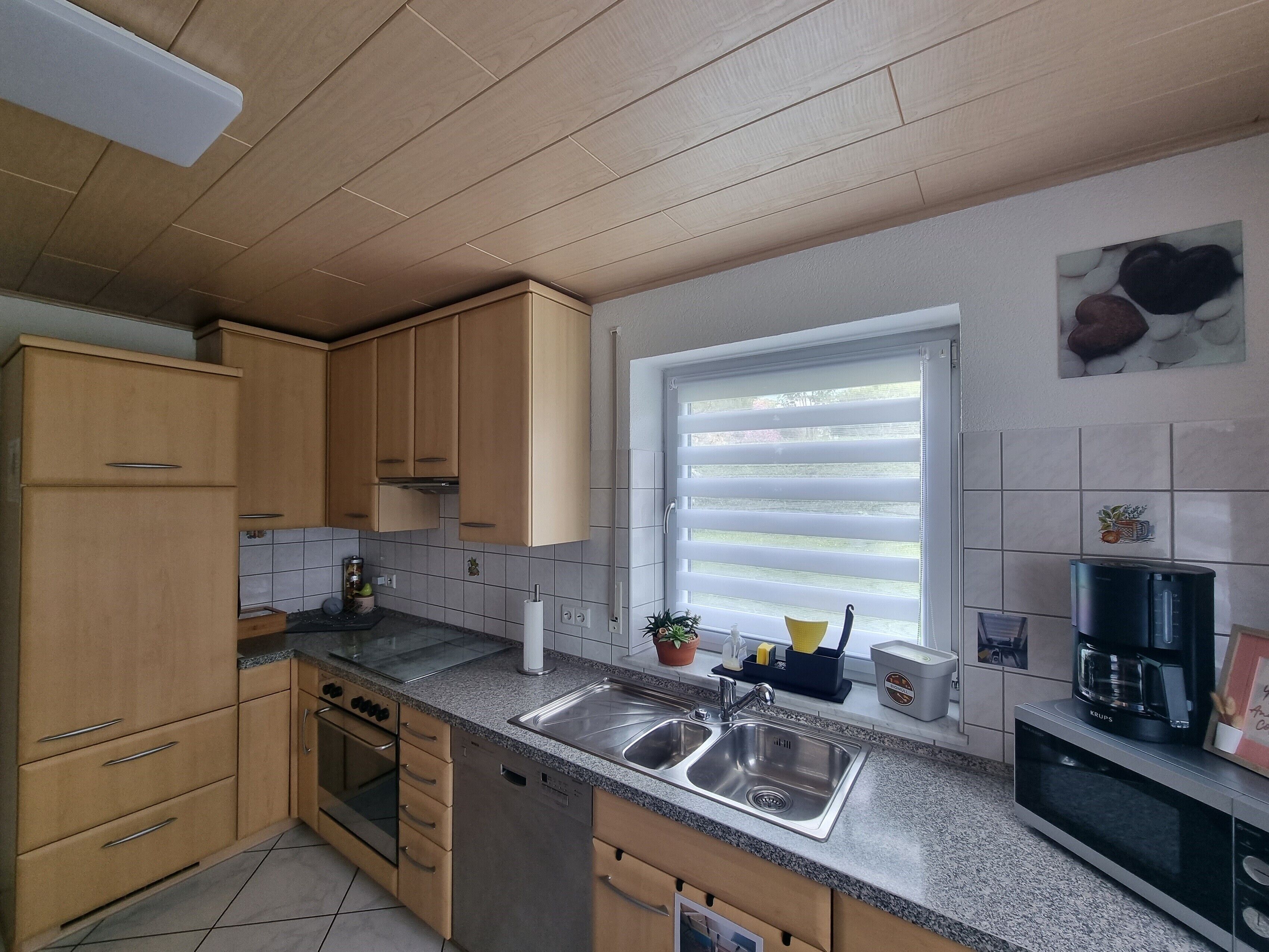 A kitchen with wooden cabinets, a double sink, a built-in oven, and a coffee maker.