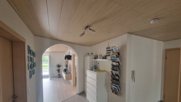 A hallway with a wooden ceiling, a white cabinet with drawers, a wall-mounted magazine rack, and a door on the right. - Holiday Apartment "Biosphärenblick" with Private Terrace, Shared Garden and Wi-Fi (Münsingen)