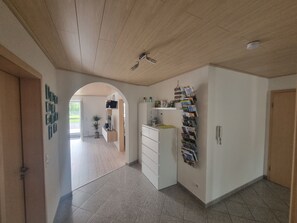 A hallway with a wooden ceiling, a white cabinet with drawers, a wall-mounted magazine rack, and a door on the right. - Holiday Apartment "Biosphärenblick" with Private Terrace, Shared Garden and Wi-Fi (Münsingen)