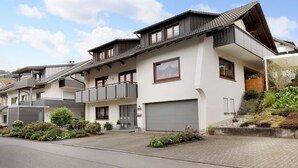 En moderne boligbygning med garage, altaner og en anlagt have.