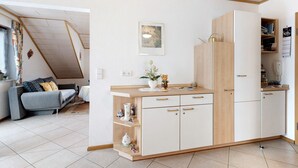 En kompakt bolig med tekøkken, sofa, spisebord og et billede i ramme på væggen.