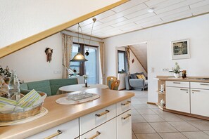 A modern kitchen with a wooden countertop, white cabinets, and a dining area with a green sofa.