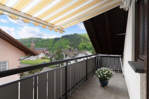 A balcony with a view of a church, a potted plant, and a metal railing.