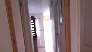 Käytävässä on värikäs, meritähtikuviollinen matto, valkoiset seinät ja puinen ovikehys.