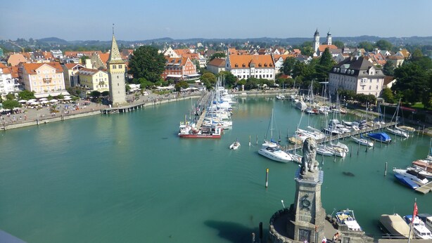A marina with boats docked, a prominent tower, and surrounding buildings. - Studio 'Sandra Scheck' with Mountain View, Private Terrace & Wi-Fi (Lindau am Bodensee)