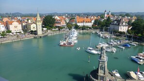 A marina with boats docked, a prominent tower, and surrounding buildings. - Studio 'Sandra Scheck' with Mountain View, Private Terrace & Wi-Fi (Lindau am Bodensee)