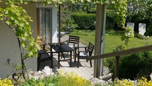 A patio with a table and chairs, a pergola with vines, and a garden with flowers. - Studio 'Sandra Scheck' with Mountain View, Private Terrace & Wi-Fi (Lindau am Bodensee)