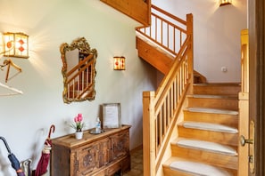 Un escalier en bois avec une rampe, un meuble en bois orné de sculptures décoratives et des luminaires fixés au mur.
