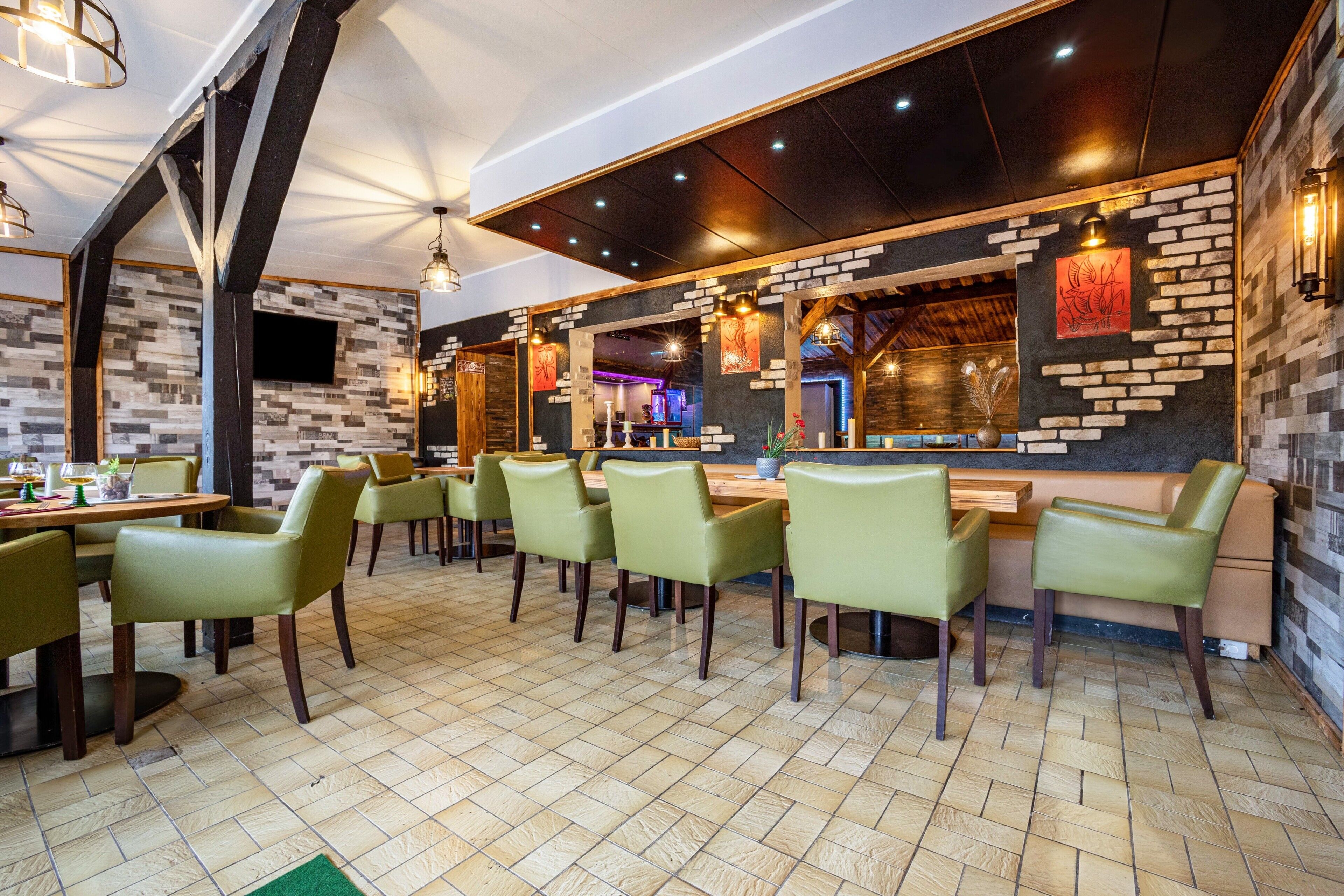 Un restaurante con pared de ladrillo, sillas verdes y suelo de baldosas.