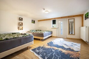 Une chambre à coucher comprenant un lit, deux canapés, un tapis, un plancher en bois, une porte et des tableaux accrochés au mur.
