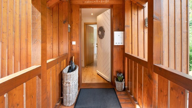 Un couloir en bois avec une porte, un panier et une plante en pot.