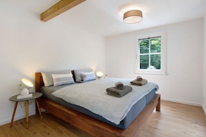 Une chambre à coucher avec un lit en bois, des lampes de chevet, une fenêtre et une table de chevet.