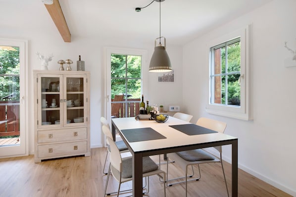 Un espace repas comprenant une table, des chaises, un buffet et un luminaire suspendu.