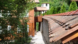 Une construction traditionnelle en bois, dotée d’un toit en tuiles et entourée de verdure.